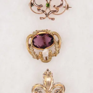 Three antique brooches including tested 14kt yellow gold set with peridot like green gemstones, and