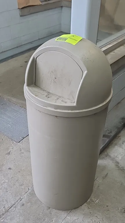 Rubbermaid trash can. Features molded plastic construction and a dome-top swing-door lid. Finished in beige. 42"H.