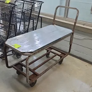 Metal 2-tier stocking cart. Features solid sheet metal upper shelf, open steel lower frame tier, and tubular push handle. 43"L. Mounted on casters. No