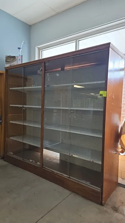 Wood frame display case with sliding glass doors. Features pegboard backing, adjustable solid metal shelving, sliding glass doors with locks and keys,