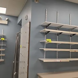 White laminate wall shelves with metal wall standards and brackets. Includes 72" and 36" shelves. Features front price tag channels on select shelves.