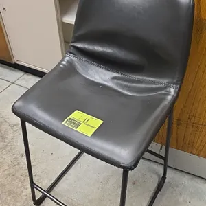Leather-upholstered bar stool. Features black padded seat and backrest with horizontal seam stitching and an integrated footrest. Mounted on a black m