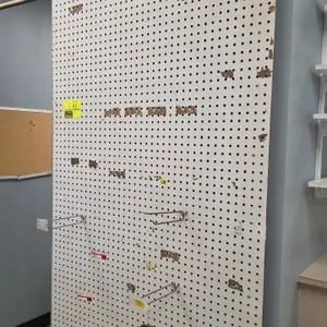 Wall-mounted pegboard display panel. Features white finish and perforated surface. Includes assorted wire display hooks with tag holders. 48" x 60".