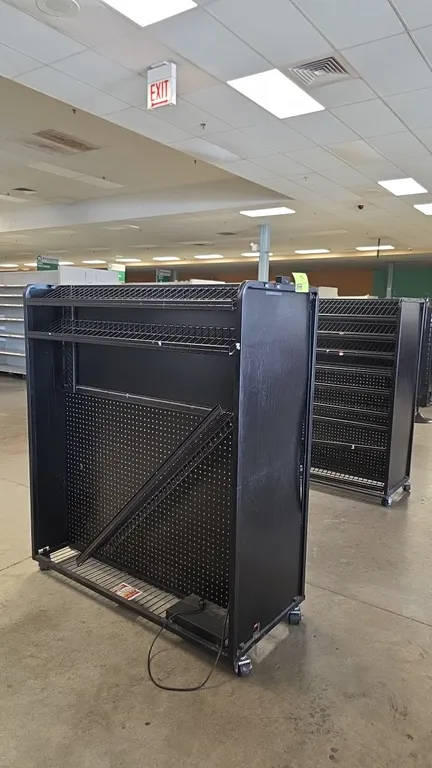 Portable metal candy and magazine merchandisers. Features black metal construction, pegboard backing, and slanted wire display shelving. Measures 50"