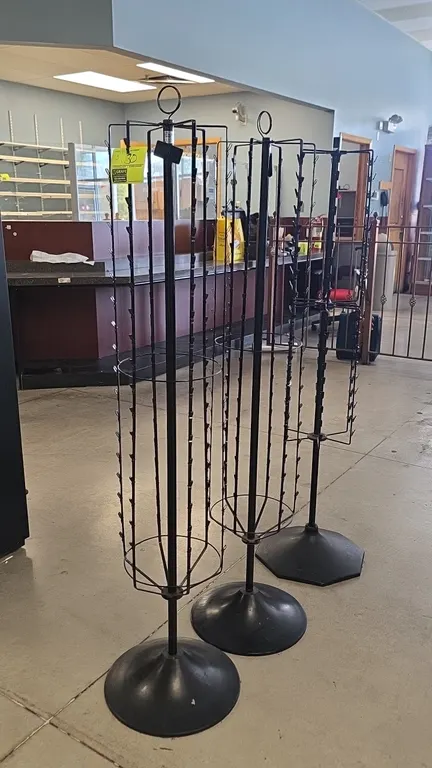 Metal rotating clip merchandisers. Features rotating wire racks with hanging display clips for bagged goods and packaged merchandise. 64"H. Mounted on