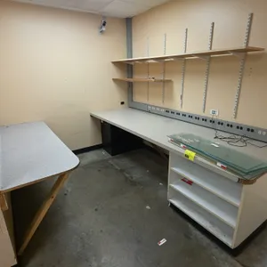 Workroom furniture and fixtures lot. Includes a 113"L laminate countertop with open storage base and black metal 2-drawer filing cabinet, a 77"L wall-