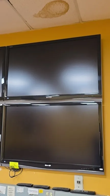 Sharp Aquos 50" flat screen televisions. Features black bezels with lower silver-tone accents. Wall mounted.
