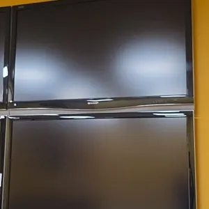 Sharp Aquos 50" flat screen televisions. Features black bezels with lower silver-tone accents. Wall mounted.