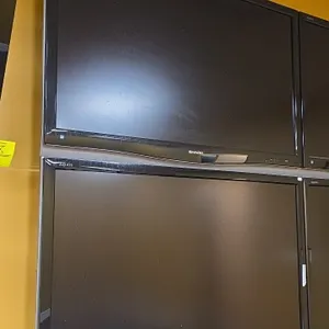 Sharp Aquos 50" flat screen TVs. Features black bezels with lower accent trim. Wall mounted. Surrounding equipment not included.