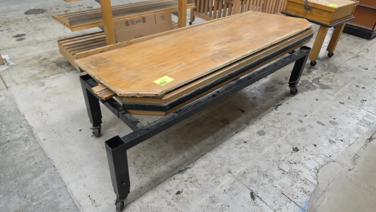 Portable wood produce display table. Features wood construction, protective perimeter bumper guard, and angled end corners. 84"L. Mounted on a black m