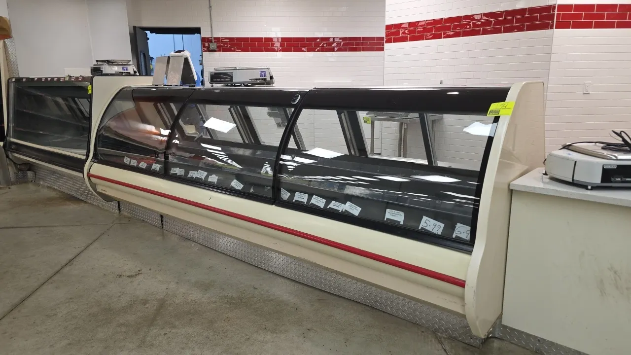 Hillphoenix curved glass deli service case. Features curved front glass, sliding rear glass doors, stainless steel rear counter ledge, and interior li