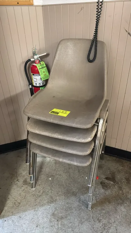 Molded poly stacking chairs. Features tan molded plastic shells, chrome-finish metal frames, and stackable design. Fire extinguisher not included.