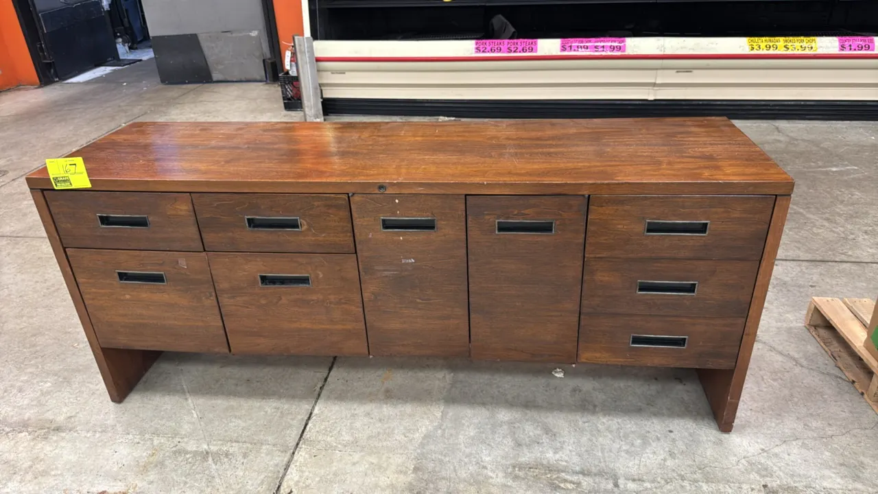 Steelcase wood credenza. Features a center two-door cabinet with interior shelf storage, seven assorted drawers with metal interiors, recessed pulls,