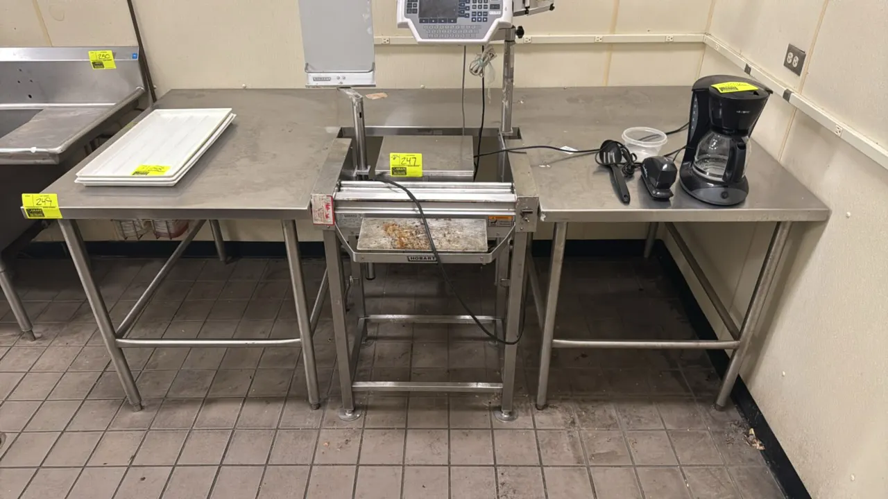 Custom stainless steel work table. Features a center cutout designed to accommodate a wrapping station, tubular stainless steel legs, and tubular cros