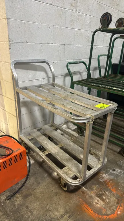 Aluminum 2-tier utility cart. Features slatted shelf construction and integrated push handle. 36"L x 20"W. Mounted on casters.