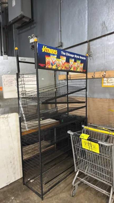 Vitner's metal multi-tier snack merchandiser rack. Features black coated wire construction, multi-tier wire display shelves with front lip retainers,