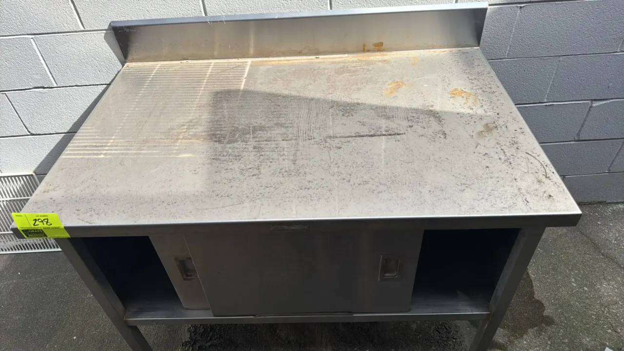 Stainless steel cabinet with backsplash. Features sliding doors and enclosed base storage. 48" x 30". Mounted on stainless steel legs with adjustable