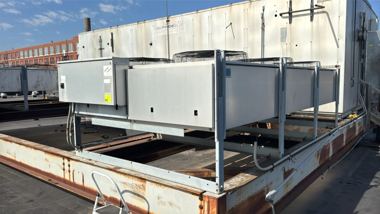 Bohn Heatcraft 6-fan air-cooled rooftop condenser. Features wire fan guards and side-mounted electrical control panel. Mounted on an elevated steel fr
