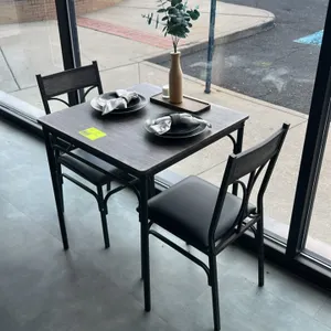 Laminate table and chair set. Includes 28" laminate top table with woodgrain finish on black metal frame, (2) metal dining chairs with cushioned black