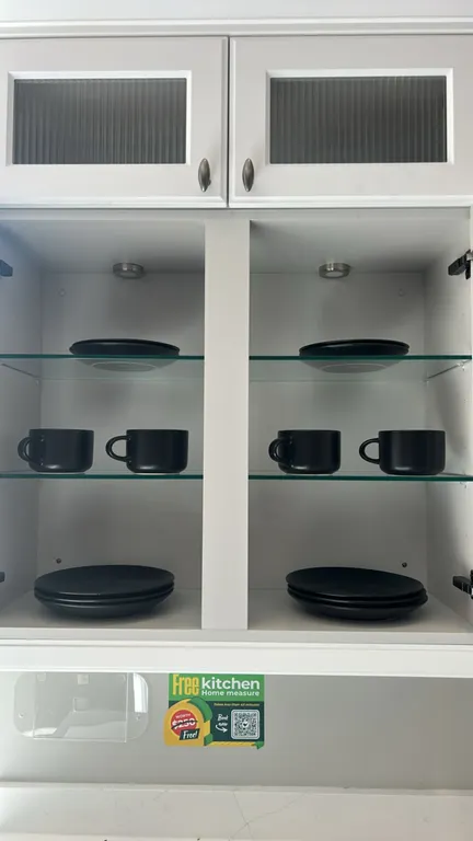 Assorted kitchen smallwares and dinnerware. Includes matte black ceramic dinner plates, side plates, and mugs; countertop utensil crock with whisk and