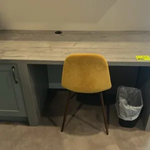 Laminate desk with cushioned chair. Desk features a gray woodgrain laminate finish, integrated single-door cabinet, and desktop cable pass-through gro