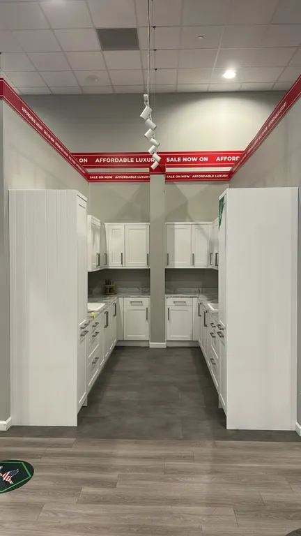 Infinity Plus laminate kitchen cabinet set. Features white shaker-style cabinetry, tall pantry cabinets, marble-look laminate countertops, (2) single-