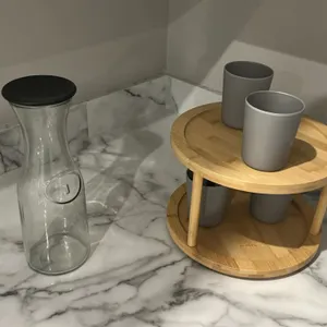 Assorted kitchen smallwares and decor. Includes a Tramontina wood cutting board, decorative artificial potted plant, glass carafe with lid, two-tier b