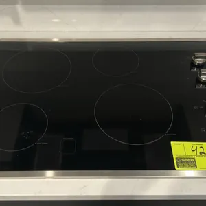 GE electric cooktop. Features black ceramic glass surface with stainless steel trim, 4 radiant cooking elements including Power Boil and Keep Warm set