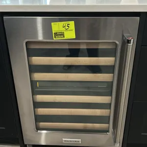 2022 KitchenAid KUWL214KSB00 undercounter wine cellar. Features stainless steel framed glass door, slide-out wine racks with wood fronts, and self-con