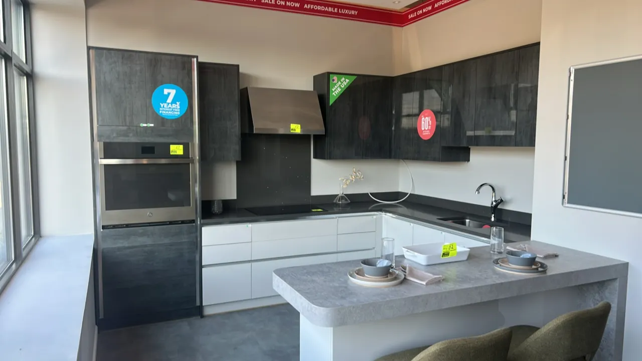 Infinity Plus laminate kitchen cabinet display suite. Features solid surface and laminate countertops, upper and lower cabinets, island with open shel