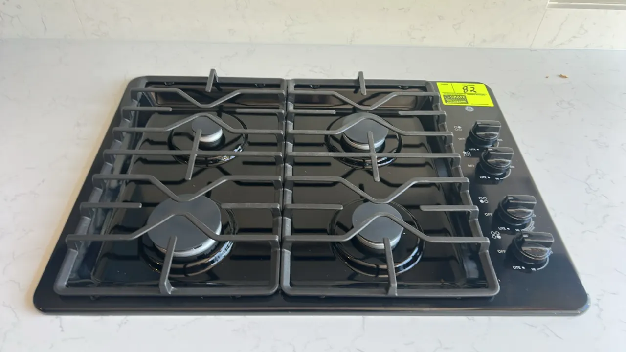 GE JGP3030DL2BB built-in gas cooktop. Features 4 gas burners with a Power Boil burner, continuous cast iron grates, and right-side control knobs. 30".
