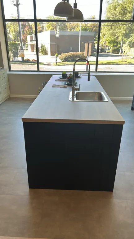 Infinity Plus kitchen island. Features dark blue laminate shaker-style cabinetry with drawers and chrome cup pull hardware, woodgrain laminate counter