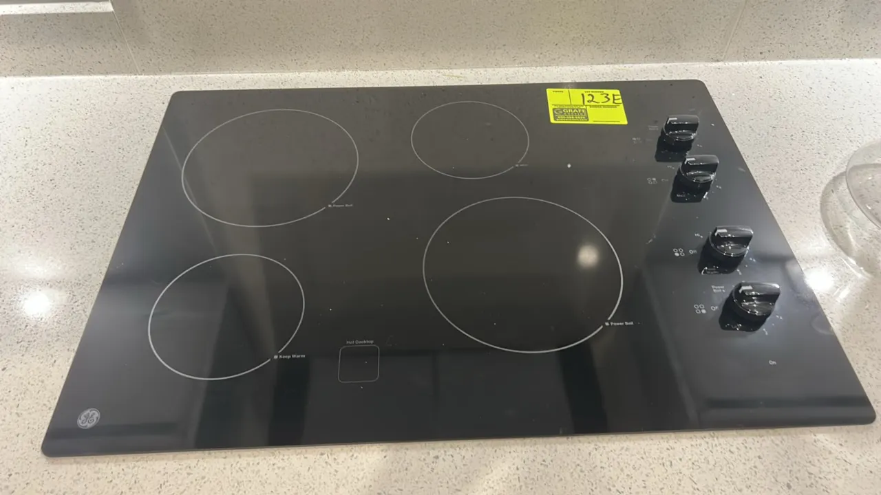 GE Appliances JP3030DJ4BB built-in 4-burner electric cooktop. Features black ceramic glass surface, side knob controls, Power Boil element, and Keep W
