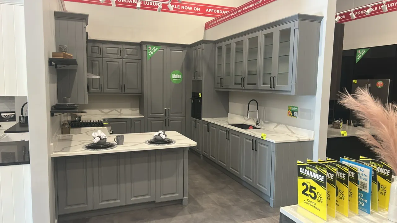 Infinity Plus laminate kitchen cabinet display. Features solid surface countertops, upper cabinets with fluted glass doors, tall pantry unit, base cab