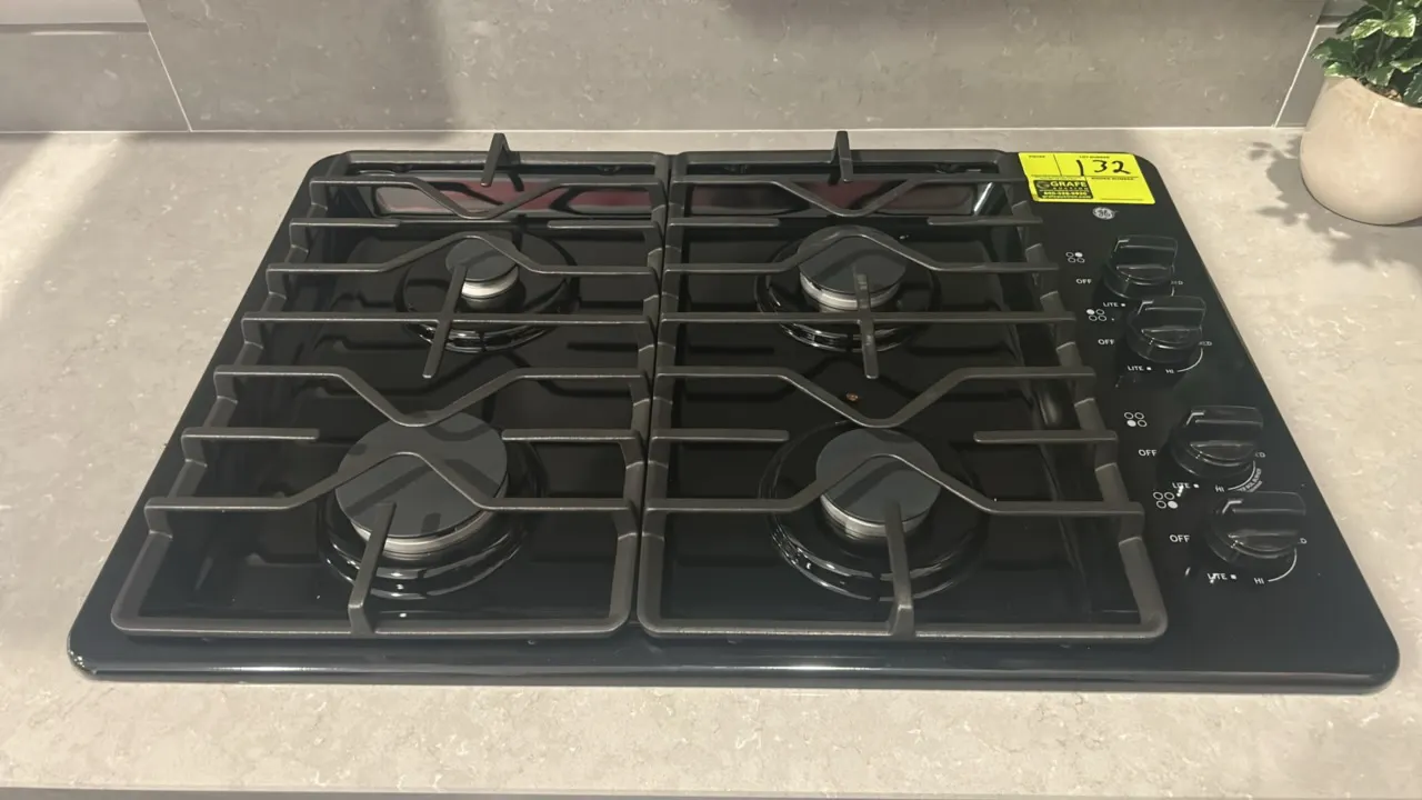 GE JGP3030DL2BB built-in gas cooktop. Features 4 sealed burners, continuous cast iron grates, right-side knob controls, and a black finish. 30"W. S/N: