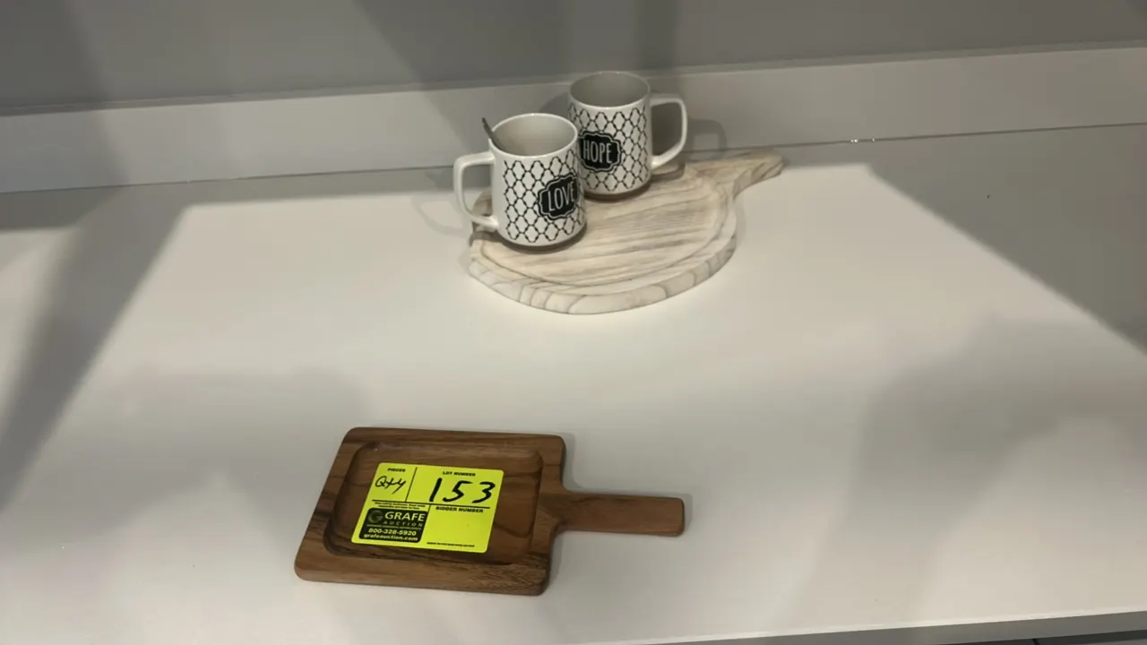 Assorted kitchen smallwares. Includes matte black ceramic dinner plates and bowls, tinted drinking glasses, ceramic mugs, wooden serving boards, and s