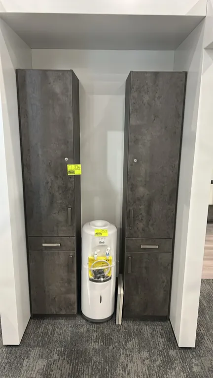 Laminate standing cabinet. Features textured weathered gray finish, upper cabinet with lock cylinder, center drawer, lower storage cabinet, and brushe