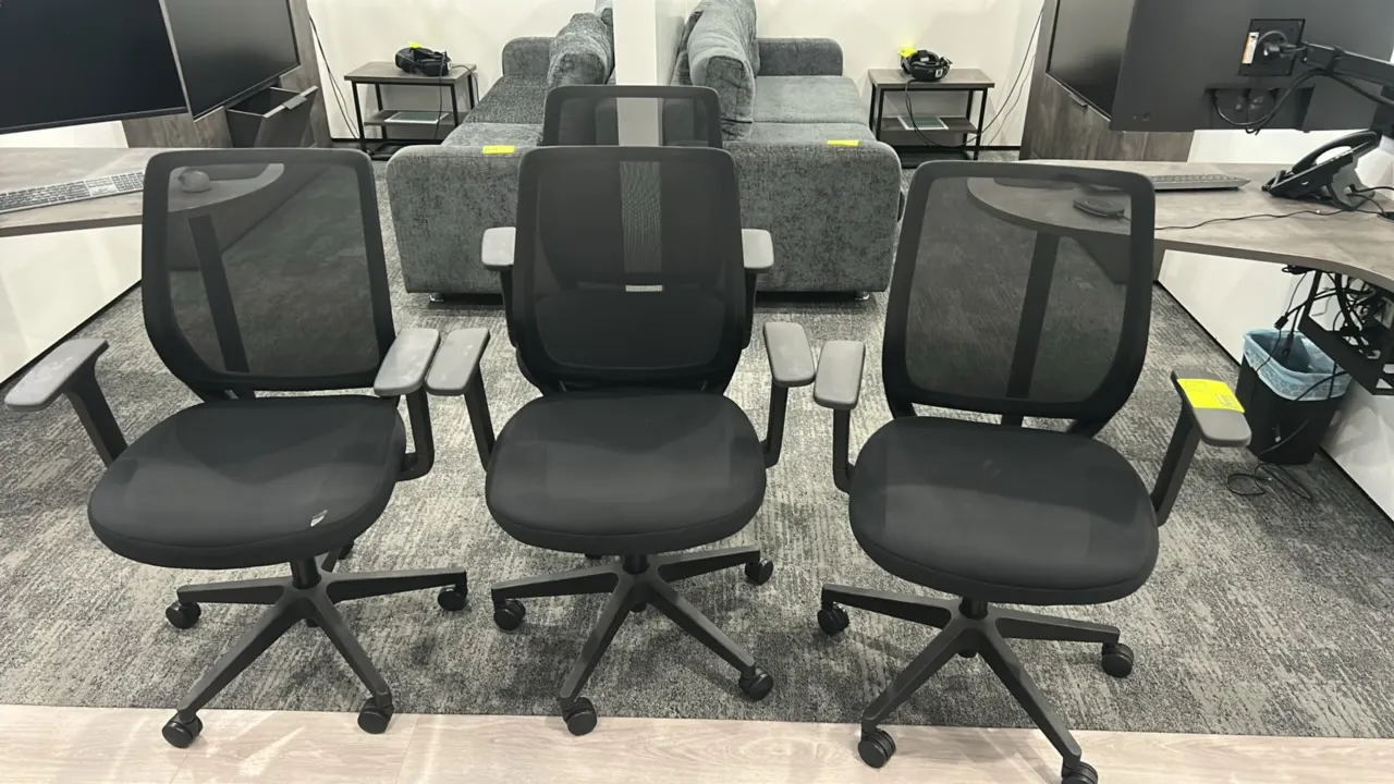 Rolling mesh office chairs. Features breathable black mesh backs, black fabric cushioned seats, and armrests. Mounted on 5-star caster bases.