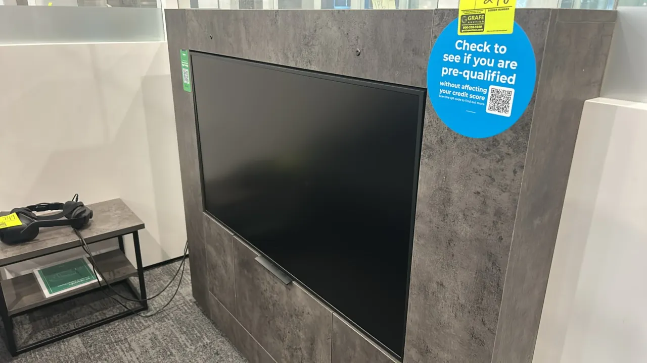 49" flatscreen built-in display monitor. Integrated into a gray textured faux-stone laminate enclosure cabinet. Features 49" display panel. Side table
