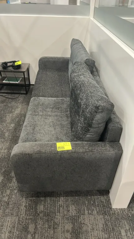 Cushioned lounge sofa. Features textured gray fabric upholstery, two-cushion seating, button-tufted back cushions, and track arms. 7'L. Note: Side tab