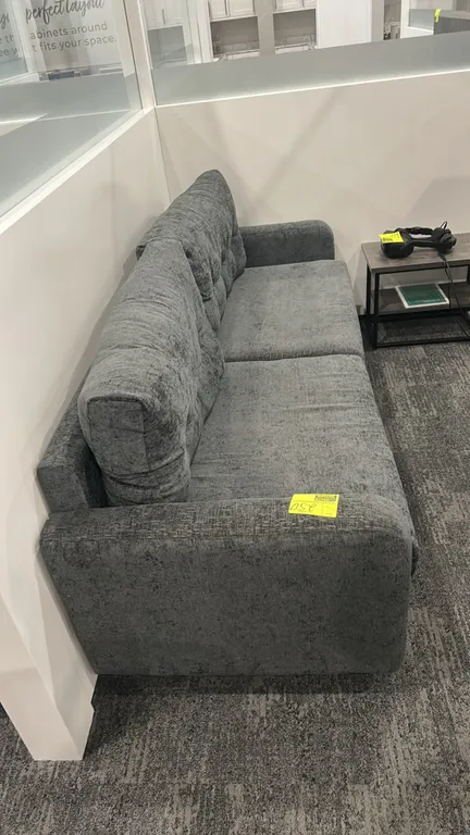 Cushioned lounge sofa. Features gray textured fabric upholstery, two seat cushions, two tufted back cushions, and track arms. 7'L. Side table not incl