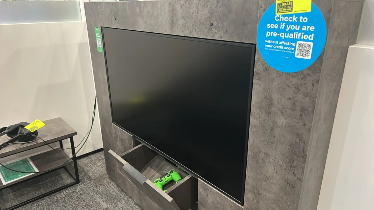 49" flatscreen built-in display monitor. Integrated into a gray faux-stone textured laminate enclosure with a lower tilt-out storage compartment. Cont