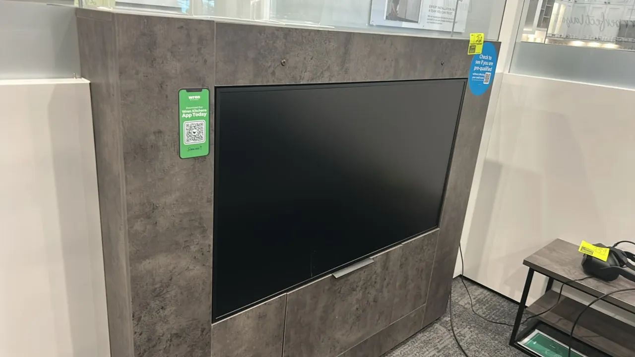 49" flatscreen built-in display monitor. Integrated into a gray stone-pattern laminate cabinet enclosure. 49" screen. Background items not included.