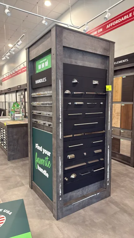Cabinet pull hardware sample display stands. Four-sided kiosk towers featuring assorted mounted cabinet handles, pulls, and knobs on display rails and