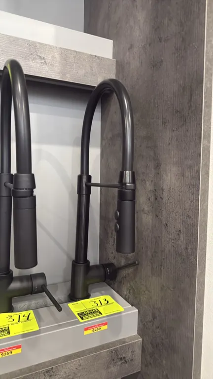 Kura pull-down kitchen faucet. Features high-arc spout, single-lever handle, and pull-down spray head with dual-function controls. Matte black finish.