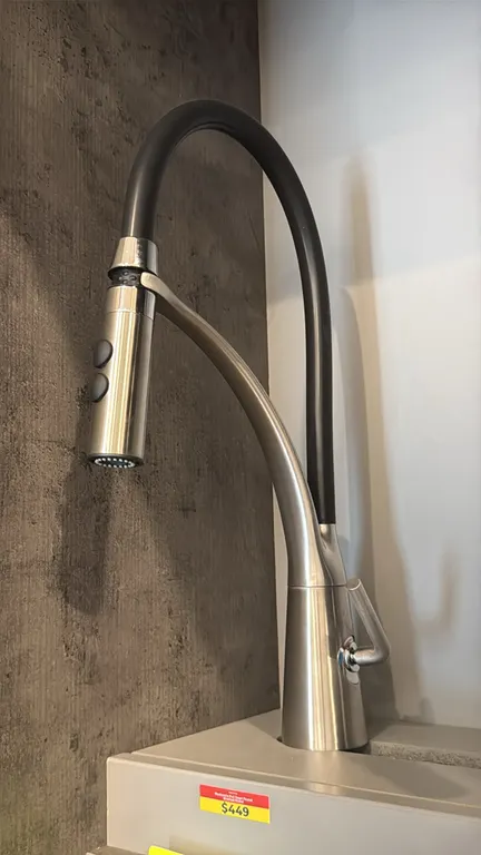 Mackenzie pull-down kitchen faucet. Features a brushed nickel finish, flexible black arched spout hose, dual-function pull-down spray head, and single