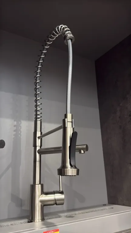 Columbia dual-spout pull-down kitchen faucet. Features a stainless steel finish, high-arc open coil spring, pull-down spray head with lever control, s