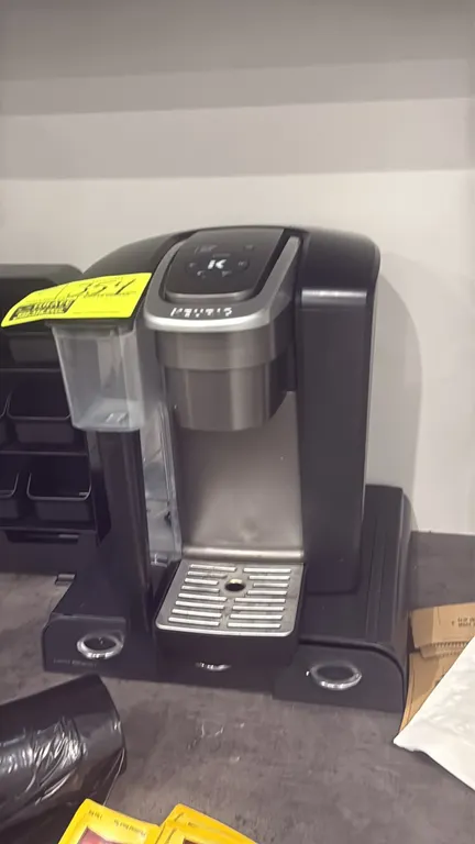 Keurig single-cup coffee brewer. Features removable water reservoir, push-button controls, and metal drip tray. Includes Mind Reader dual-drawer organ