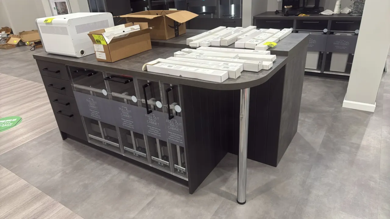 Kitchen island cabinets and countertops with wall cabinets. Features dark gray finish, laminate countertops, chrome support leg, pull-out base cabinet