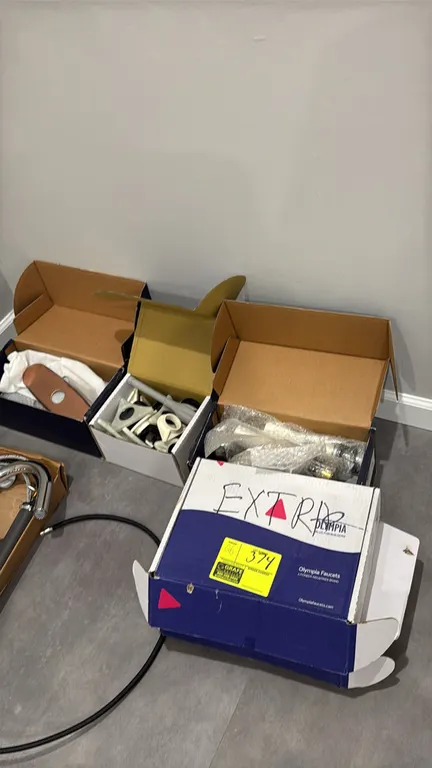 Assorted faucet hardware in (5) boxes. Includes Olympia Faucets components, pull-down spray heads, flexible hoses, deck escutcheon plates in copper an